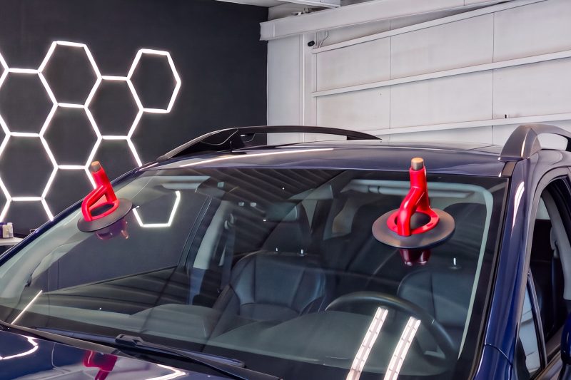 Two red suction cups set on the windshield of a dark blue car in the bay