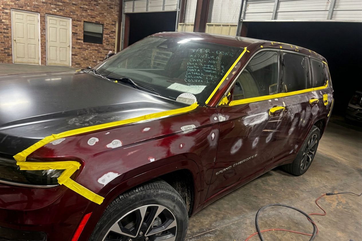 Before: a dark red SUV masked off, the repaired panels down to primer